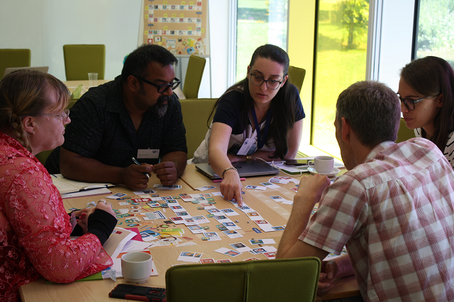 Five people around a table creating a journey together using the Our Journey cards and poster